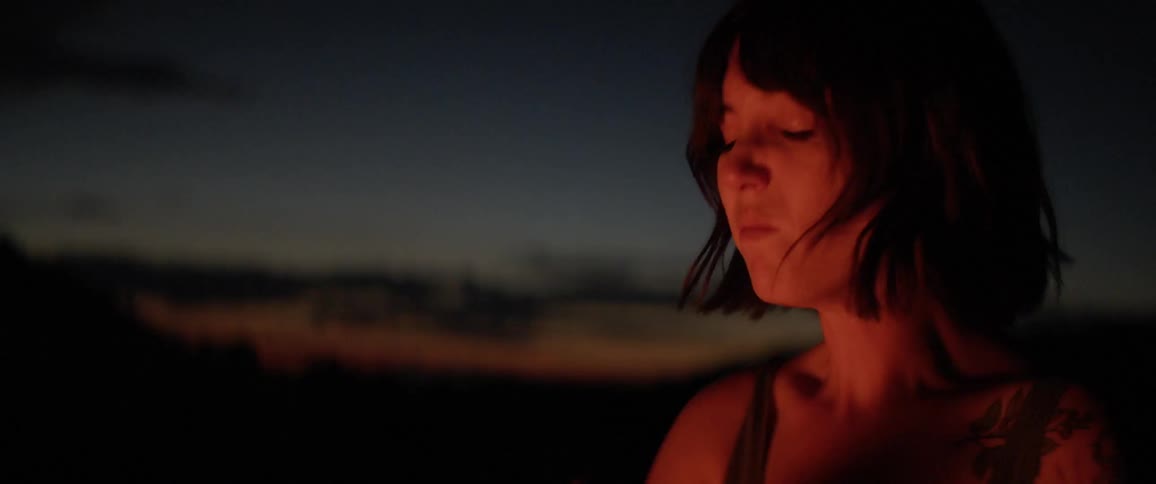 A woman wipes away tears while standing outside over a fire