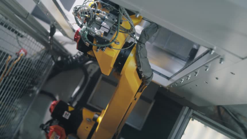 A robotic machines arm moves through an opening and then pulls back out