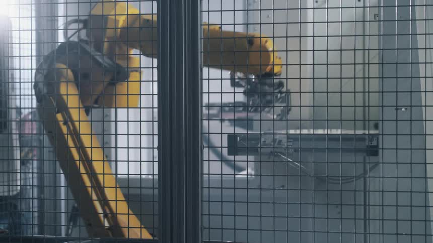 A robot builds something and presses buttons inside a steel structure