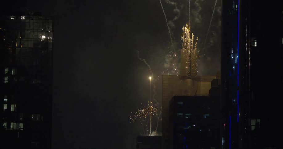Fireworks explode near city skyscrapers at night