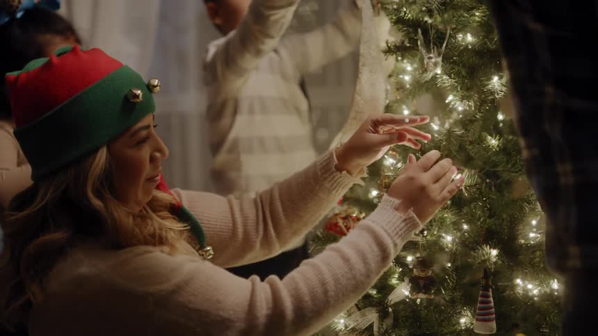 A family works together to decorate a christmas tree