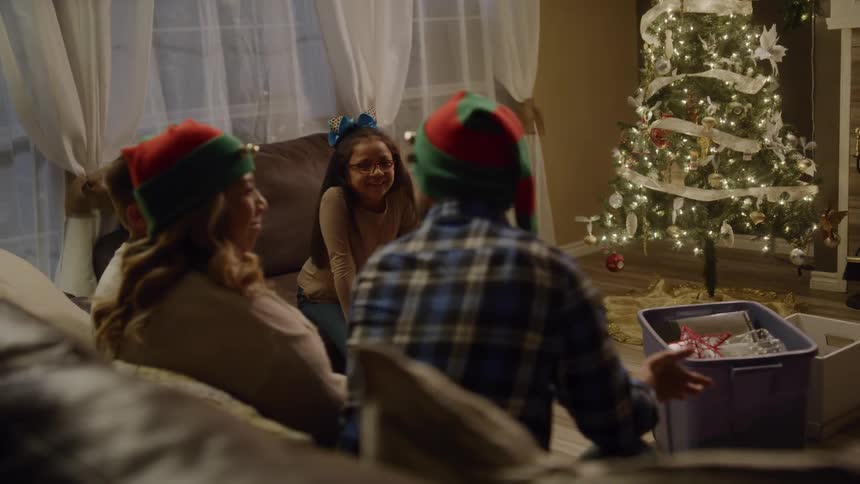Family laughs in living room near christmas tree