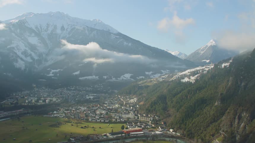 A large town sits nestled between gorgeously majestic snow capped mountains
