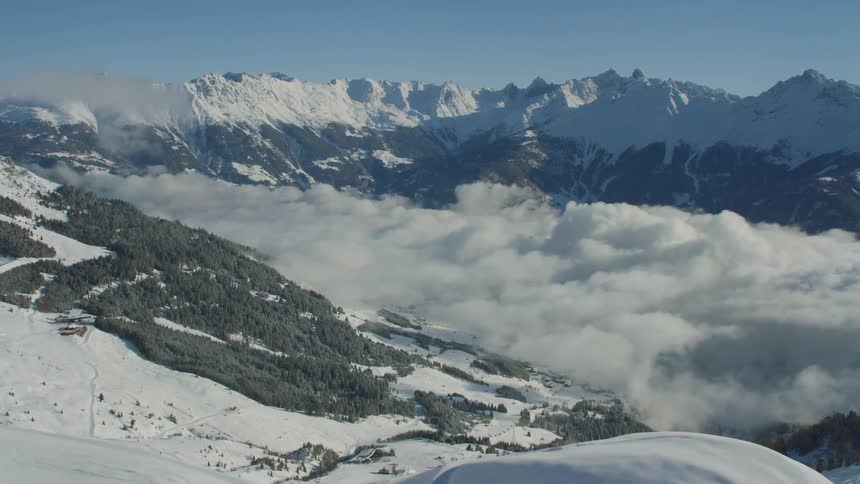 An aerial footage of a snowy mountain above the cloud