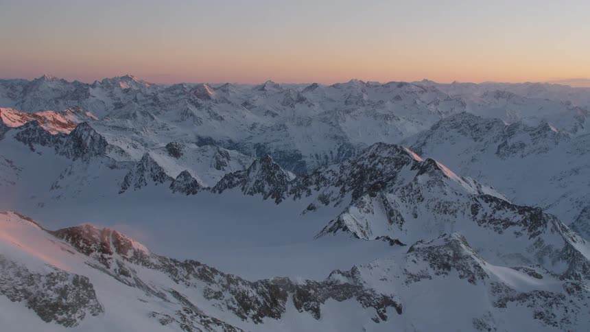 A snowy mountain range at sunset
