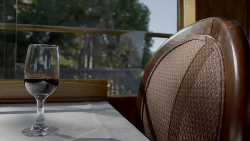 An empty seat with a glass of wine in a moving train
