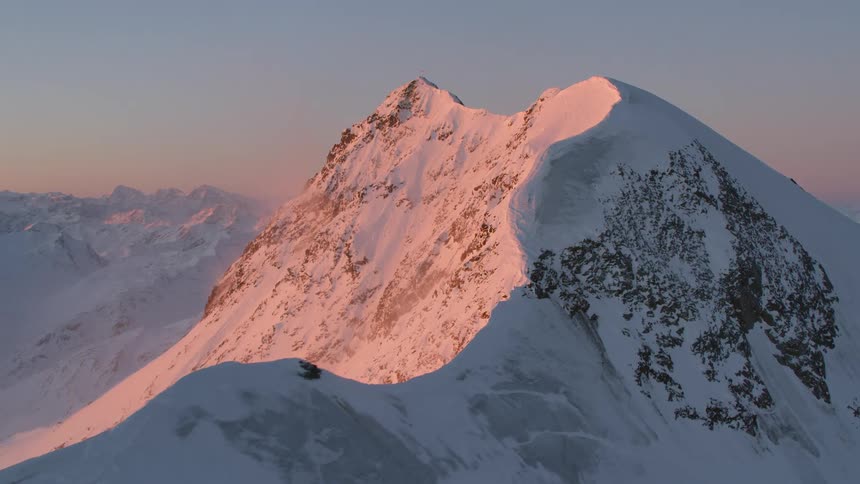 Aerial view of snow capped mountain peak at sunset