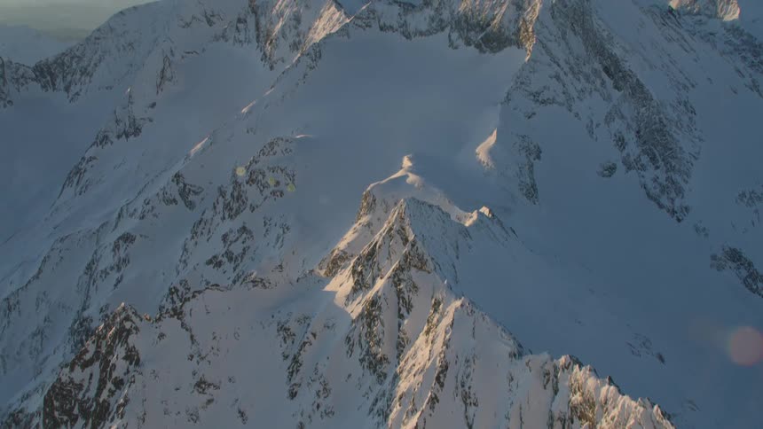 Snow covers peaks and slopes of mountain under a clear blue sky