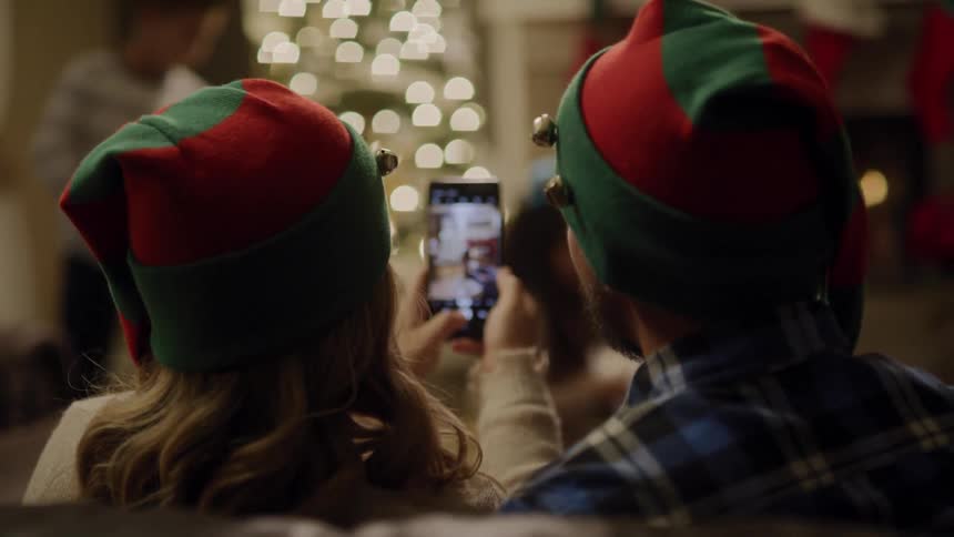 Couple take selfie while kissing and wearing christmas hat