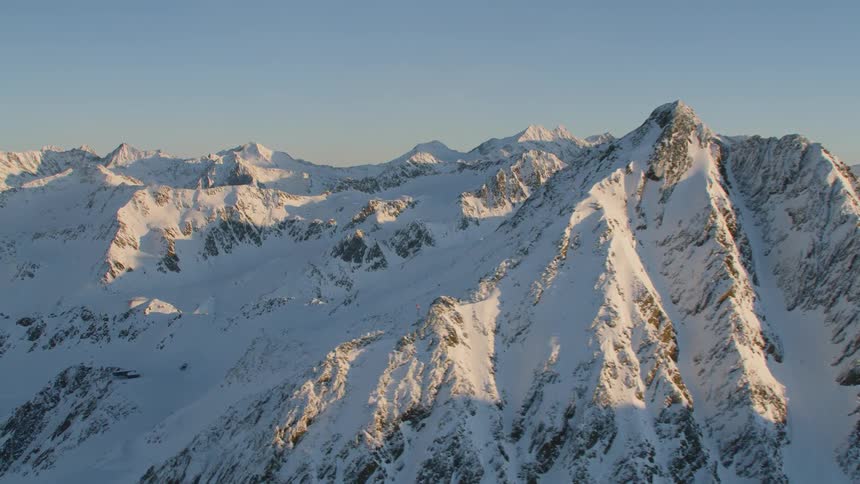 An expansive mountain range is completely covered in a thick layer of snow