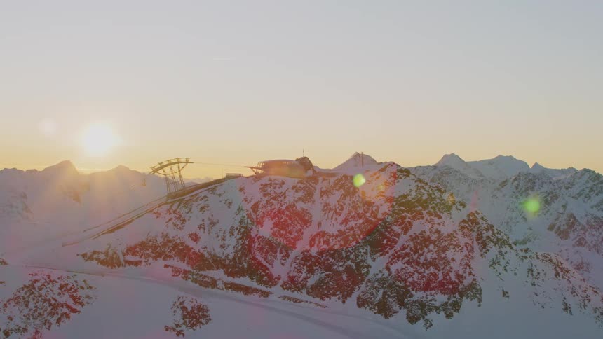 A ski lift moves a lift chair down the mountain as the sun rises