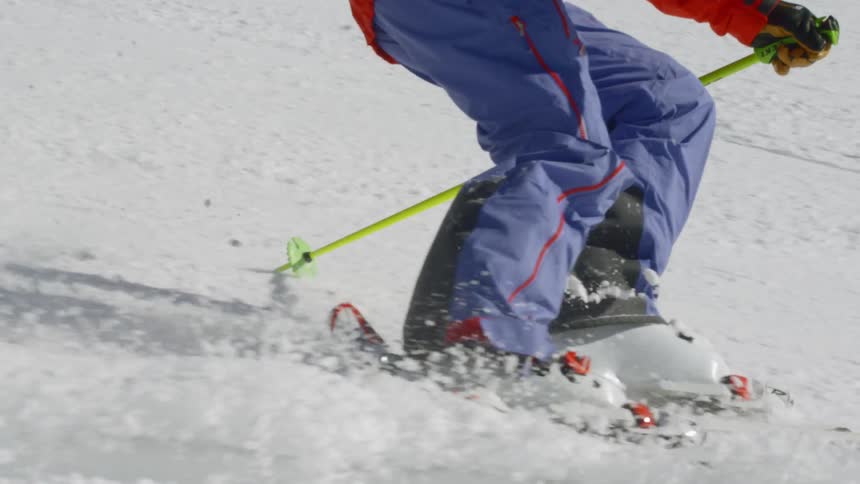 Skier skis down slope wearing bright red ski jacket