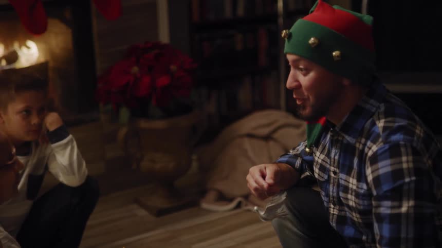 A father and his children put decorate for christmas while wearing elf hats