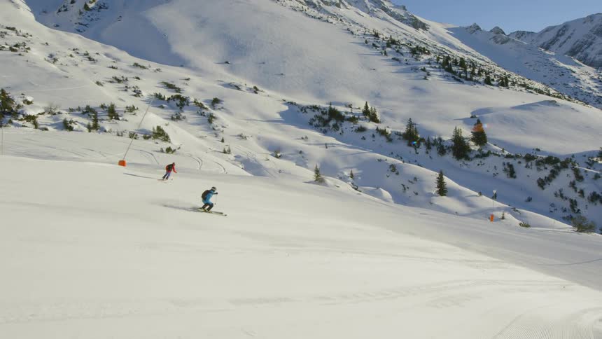 A pair of skiers skiing down a slope