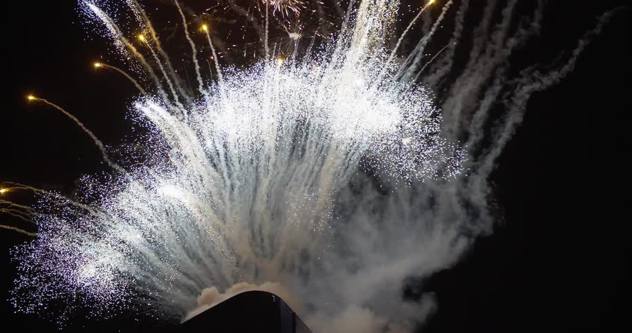 Multiple fireworks being shot and exploding in the air at night