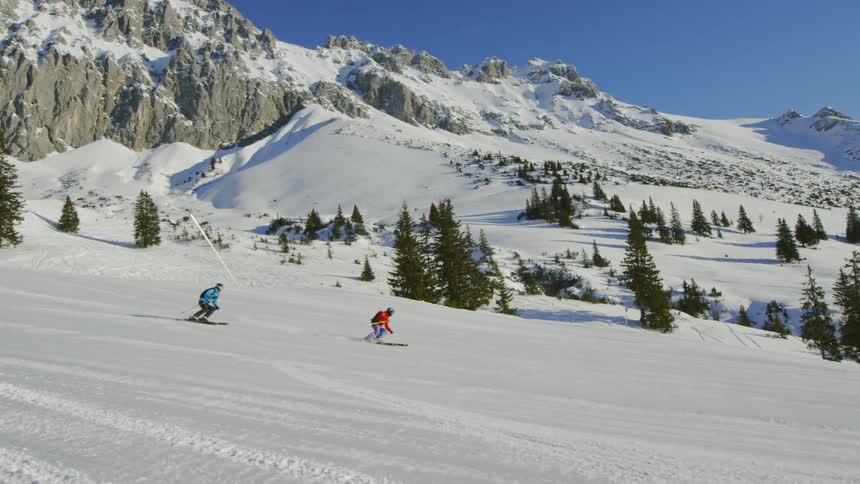Two people ski together down the slope