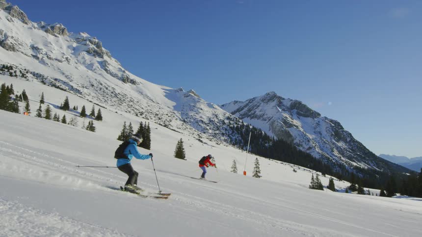 Skiers head down a groomed trail