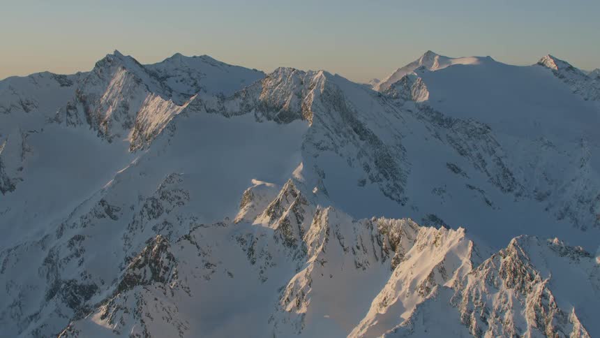 An aerial footage of snowy mountain apex at dawn