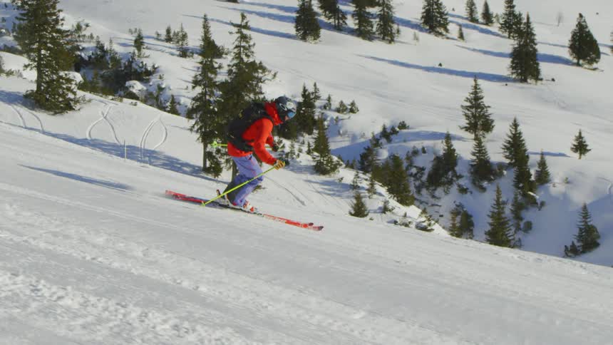 A person skis down a groomed trail