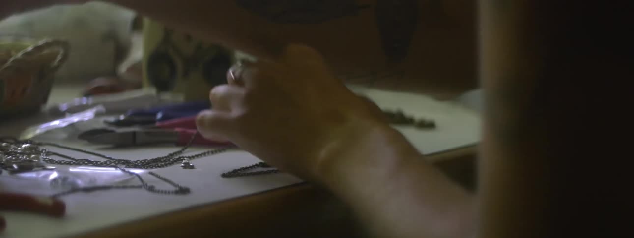 A woman is creating jewelry at a table