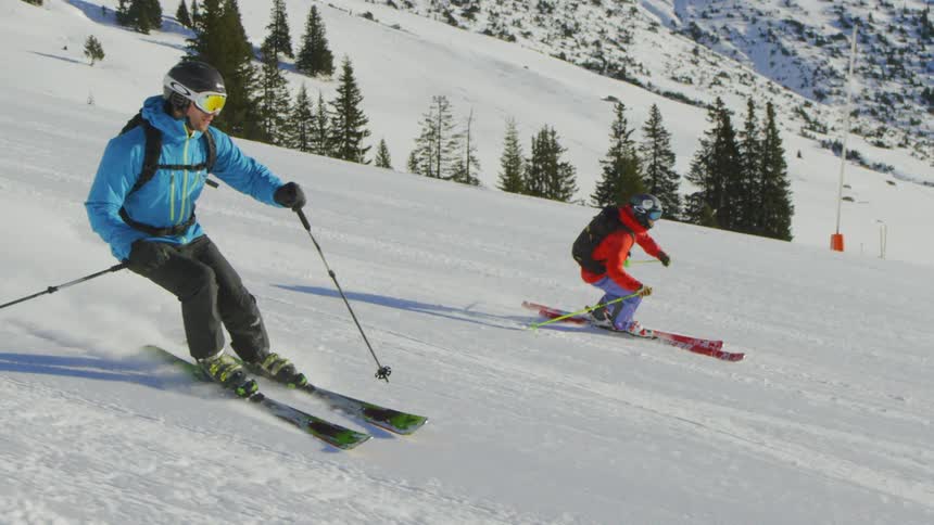 Two skiers race down the snow covered slope