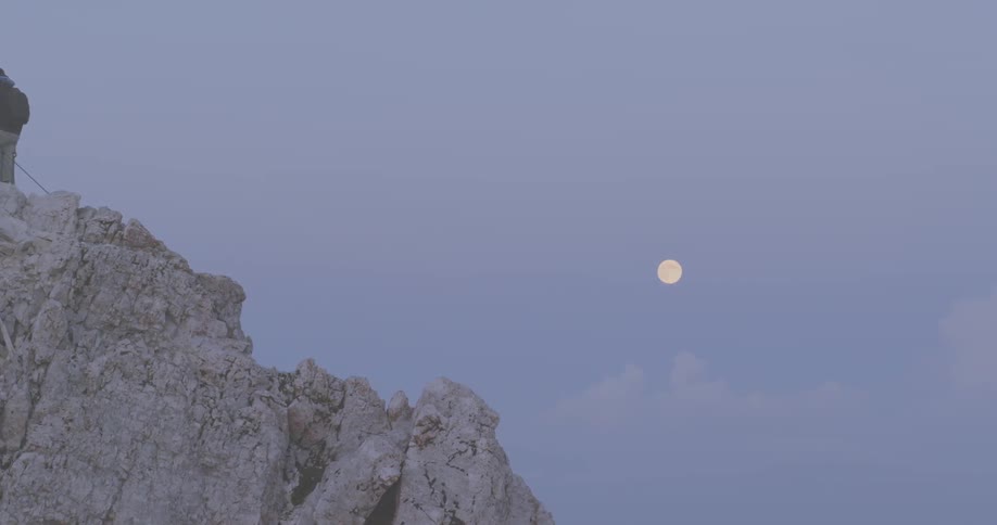 A man stands on the summit of a mountain