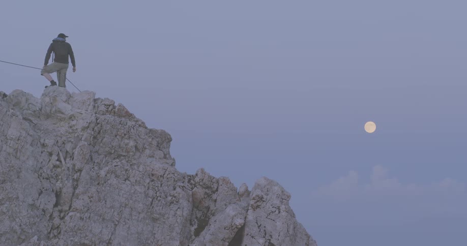 A person stands on a high mountain cliff