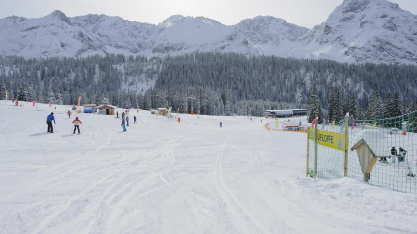 Skiers ski on the snowy land near the snow covered mountains