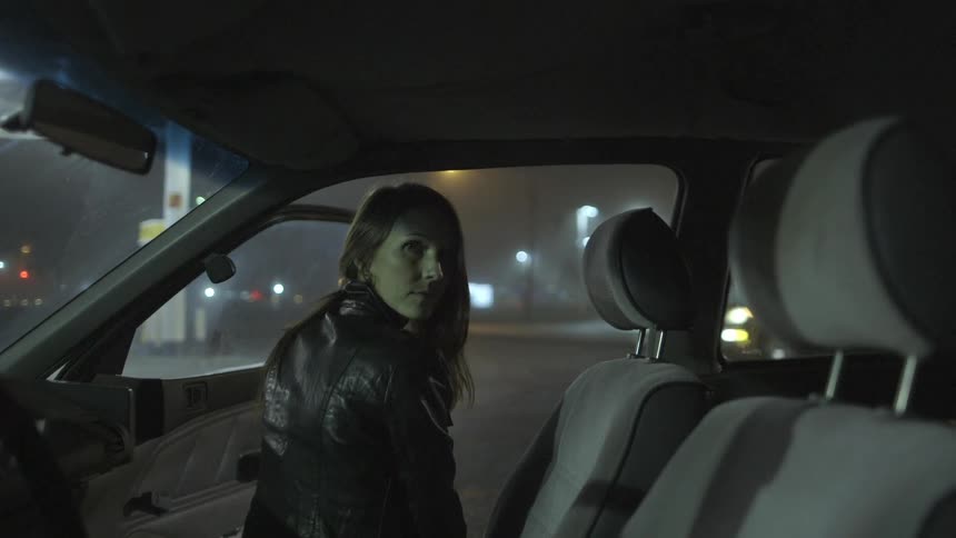 A woman in a leather jacket sitting in a car