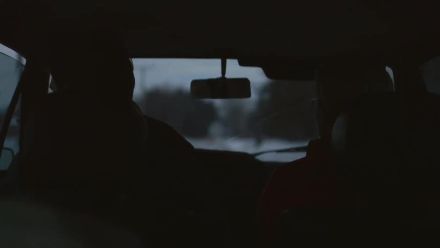 Two people in the front seat of a car in the evening