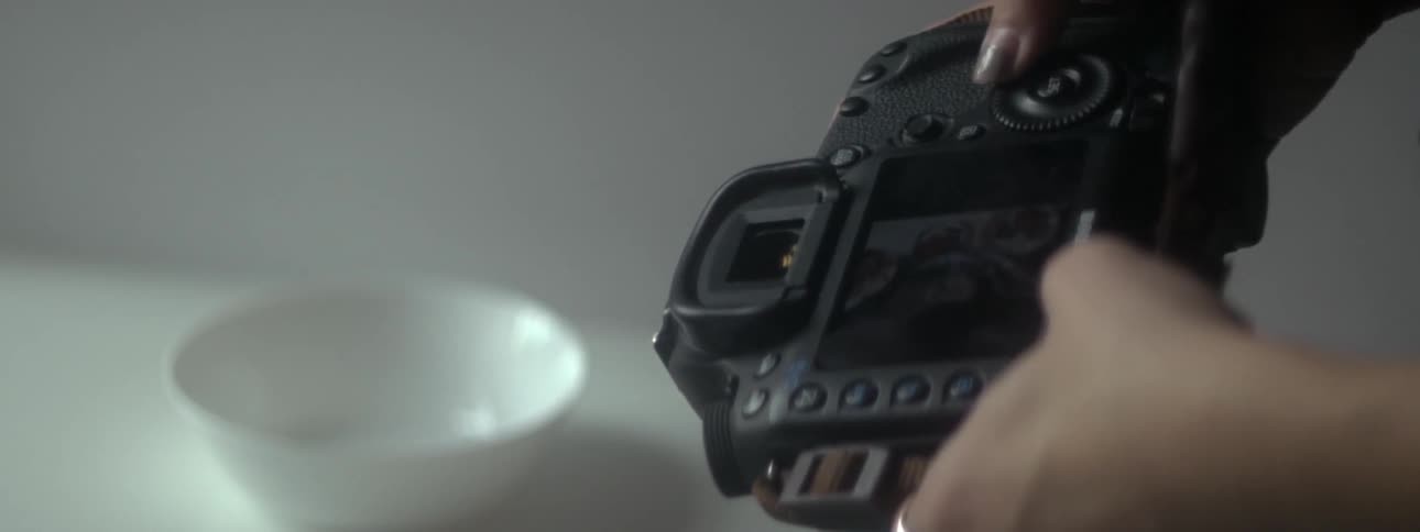 A woman going through pictures and turning the dials on her camera