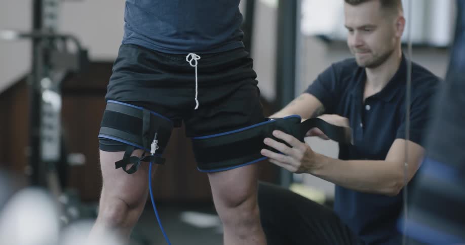A man puts cuffs on another adult males legs