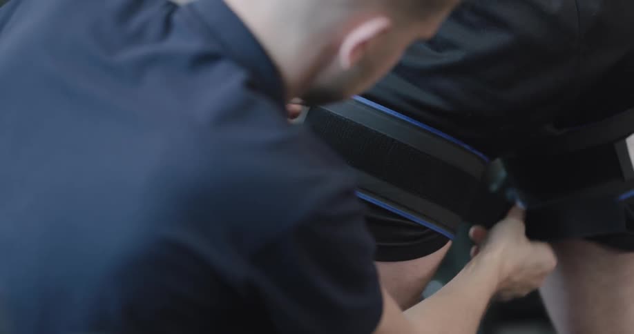 Man fastens straps onto legs of another man