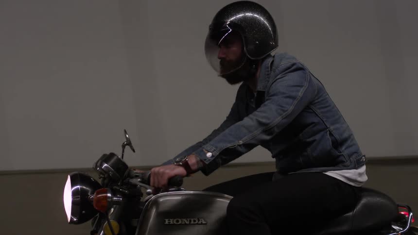 A man in a denim jacket riding a motorcycle