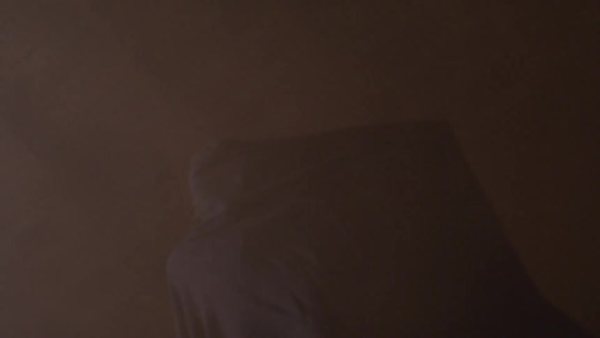 Person moving under piece of cloth on foggy room