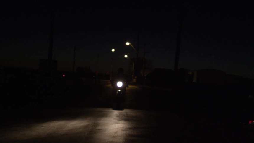 Someone riding a motorcycle down a dark street at night
