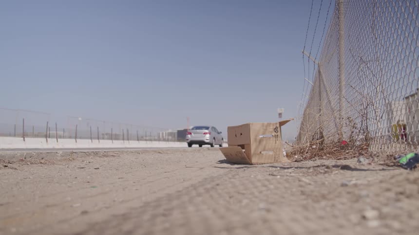 Cars driving down a road near a wired fence