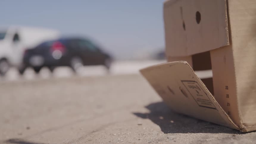 Cars are driving on a road and a box is on the side of it