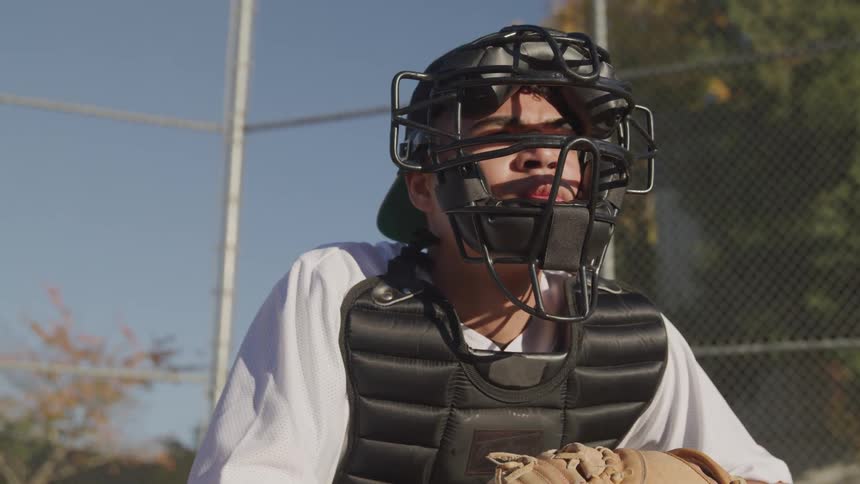 A man wears a baseball catchers mask and glove