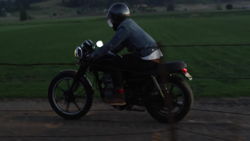 A man rides his motorcycle on a dirt road