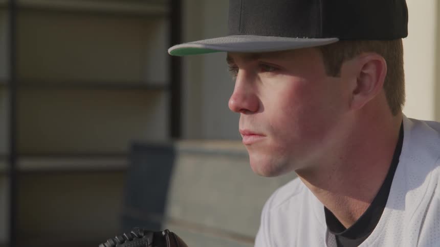 A baseball player sitting on a bench in the dugout