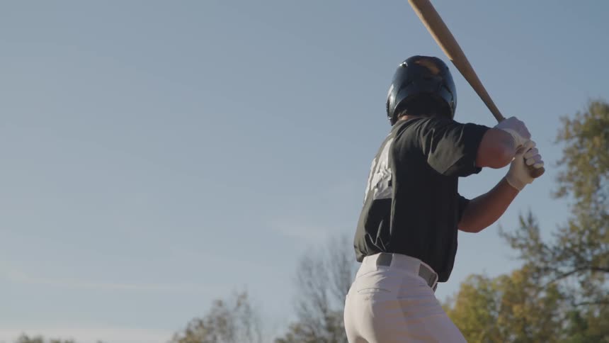 A baseball player stands in a batters stance and then swings at a pitch