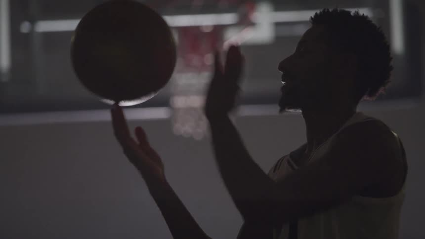 A basketball player on the court twirls and spins a basketball on his finger