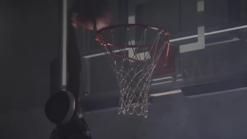 A man with a headband dunking a basketball in a hoop