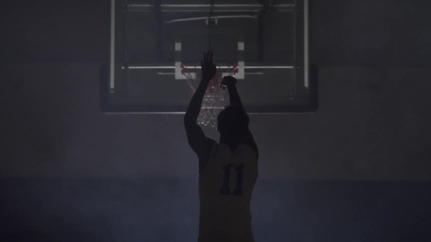 Black man shoots a basket in the dark basketball court