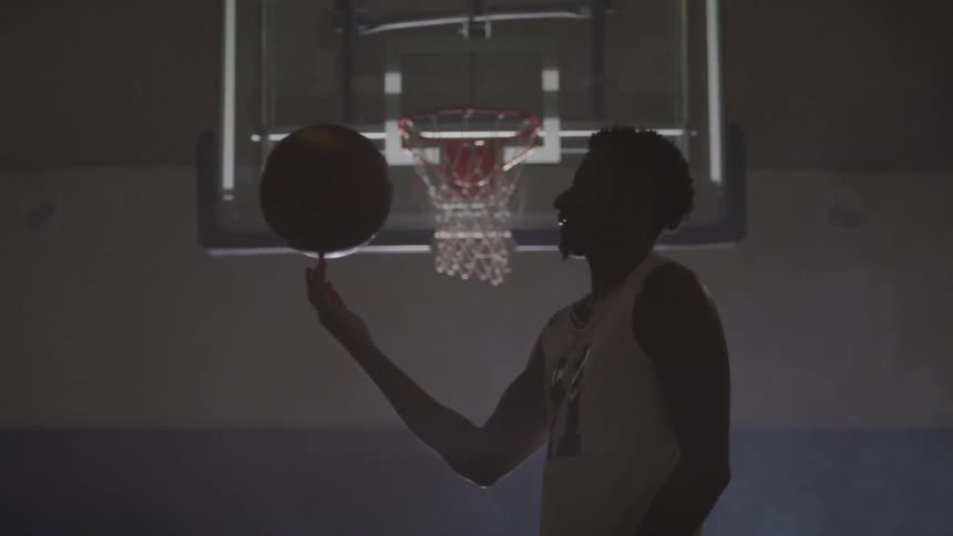 Man spins basketball in front of basketball hoop