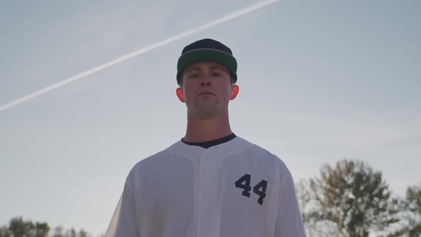 A guy is wearing a baseball jersey and standing outdoors