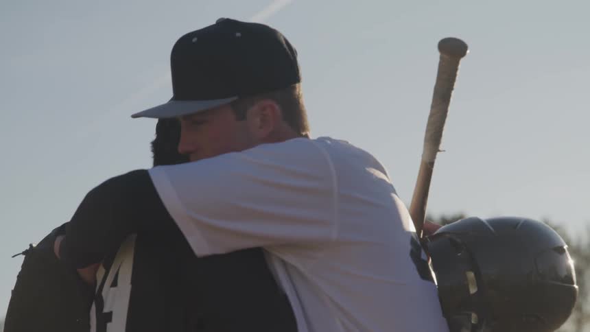 Players from competing baseball teams congratulate and embrace each other