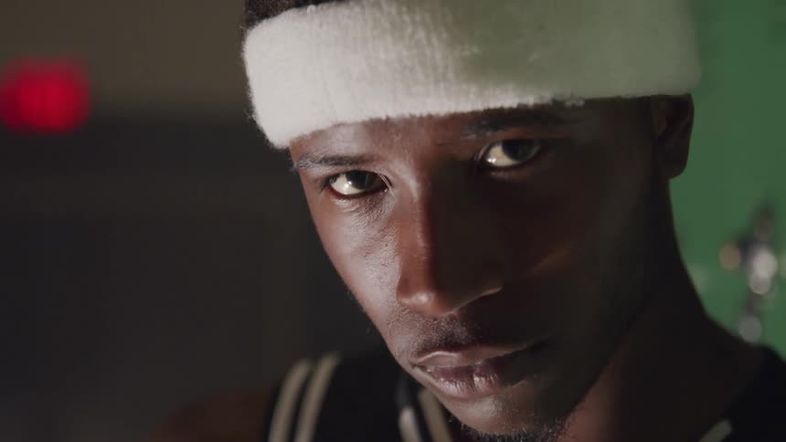 Black basketball player raises his head and looks at camera in the room