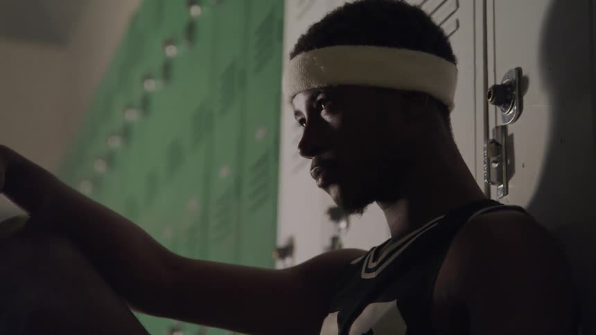A young black man contemplatively thinking in the locker room